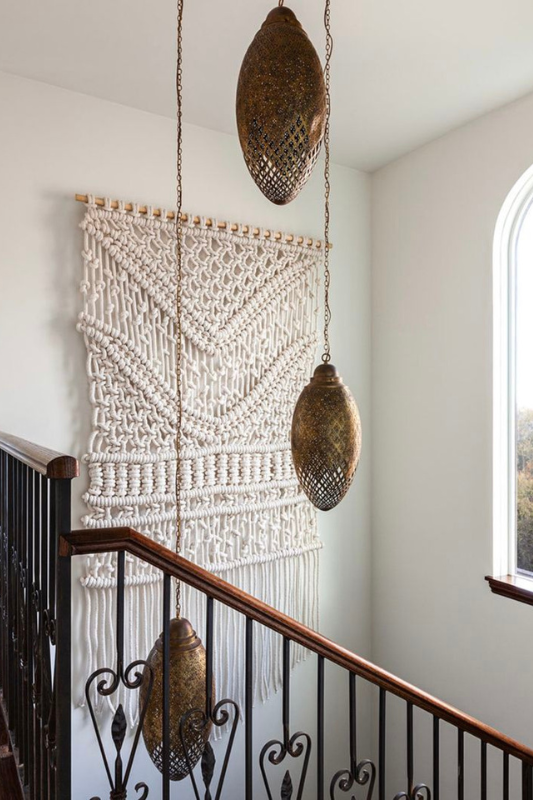 Boho staircase wall decorated with a large macrame wall hanging and vintage pendant lights