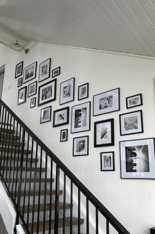Modern staircase gallery wall with large black frames and black-and-white architectural photography