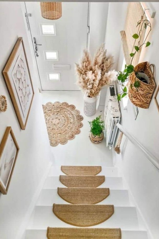 Bright boho staircase decorated with woven baskets, greenery, framed art, and natural jute stair runners