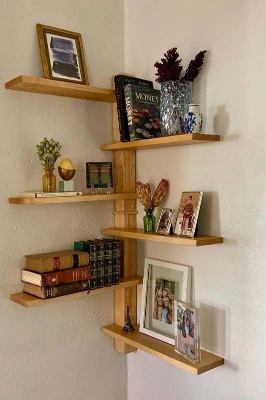 Corner floating shelves used for vertical storage and decor in a small apartment