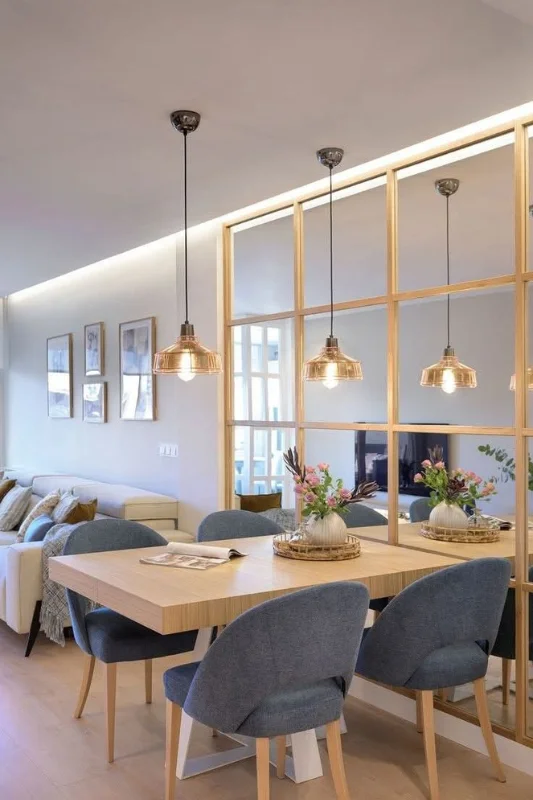 Studio apartment dining area with mirror partition used to reflect light and divide space