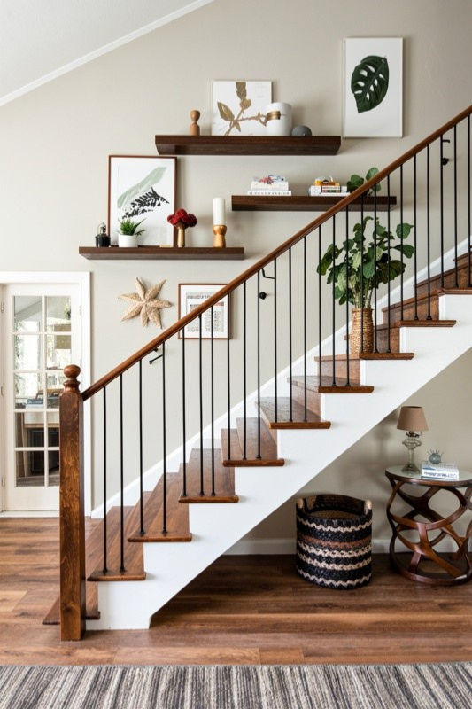 Staircase wall decorated with floating wood shelves, botanical art, plants, and simple accessories