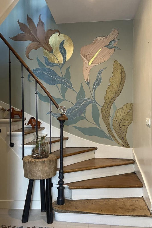 Large botanical floral mural decorating a staircase wall with wood steps and black railing