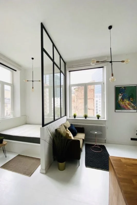 Studio apartment with glass partition separating the bed nook from the living area