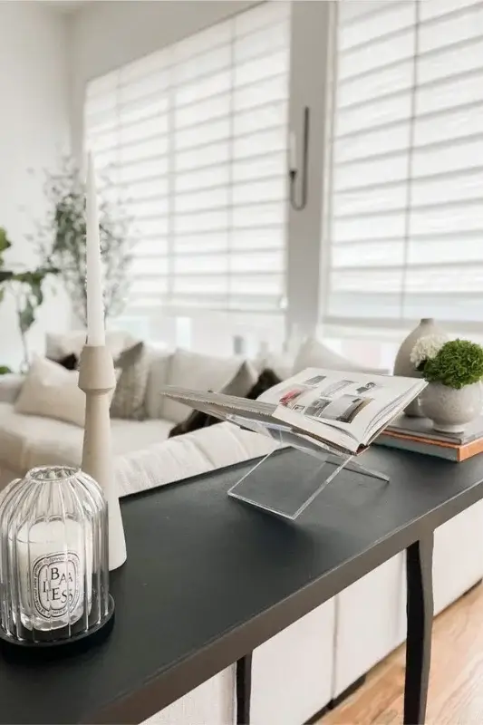 Modern black console table behind sofa styled with candles, glass decor, and an open book for clean, minimalist behind the couch styling