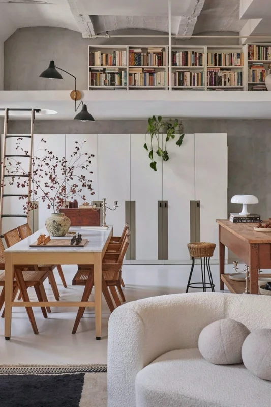 Studio apartment layout with overhead bookshelf storage, dining table, and open living area