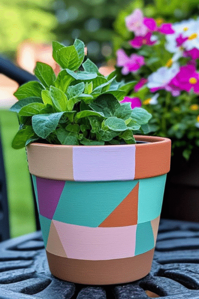 Vibrant geometric hand-painted flower pot in pastel and bold shades of teal, lilac, peach, and terracotta. Perfect for spring and Easter garden decor, this DIY planter adds a cheerful and artistic touch to patios, balconies, and outdoor tabletops. Ideal for showcasing seasonal greenery or colorful blooms.