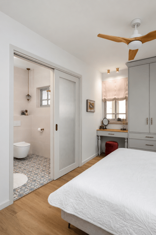 Light wood pocket door saving space in a small neutral bathroom with a compact vanity