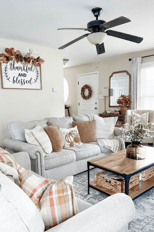 Neutral farmhouse fall living room decor with plaid pillows, warm textures, wood furniture, and subtle autumn accents