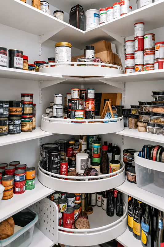 Corner pantry with rotating Lazy Susan shelves organizing spices, canned foods, sauces and cooking essentials.
