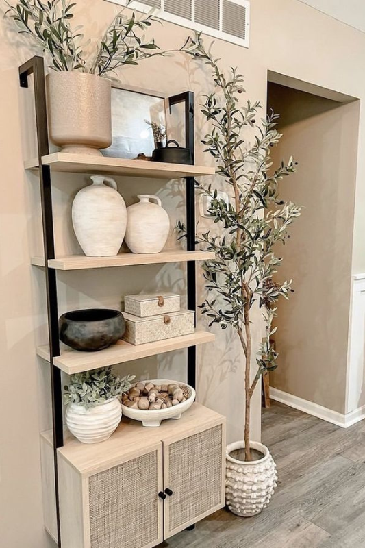 Open shelves above a closed cabinet styled with sculptural pottery, abstract decor, and natural branches in a modern entryway.