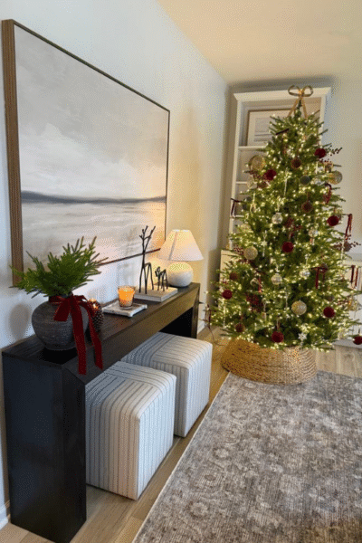 Neutral Christmas console table with Scandinavian ceramic village houses, mini trees, and woven baskets.