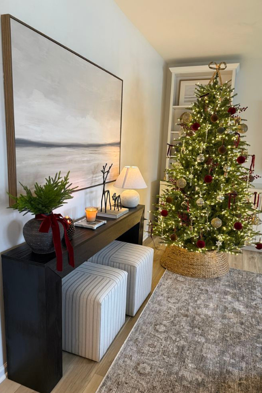 Neutral Christmas console table with Scandinavian ceramic village houses, mini trees, and woven baskets.