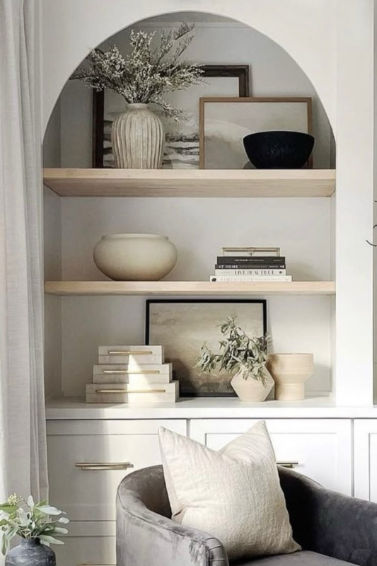 Built-in shelves styled with layered vintage gold frames, sculptural elements, and curated art in a transitional space.