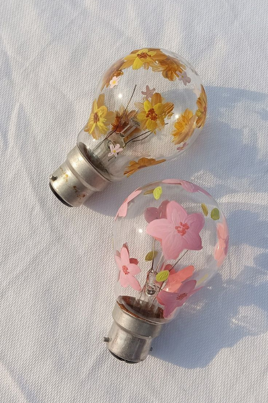 Upcycled light bulbs decorated with pressed flowers for a creative summer DIY craft idea