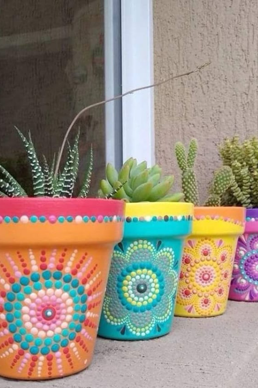Hand painted terracotta pots with colorful mandala patterns used as summer plant decor