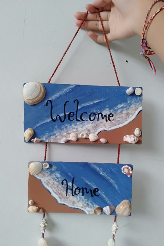 Welcome home beach sign painted with ocean colors and decorated with shells for summer home decor