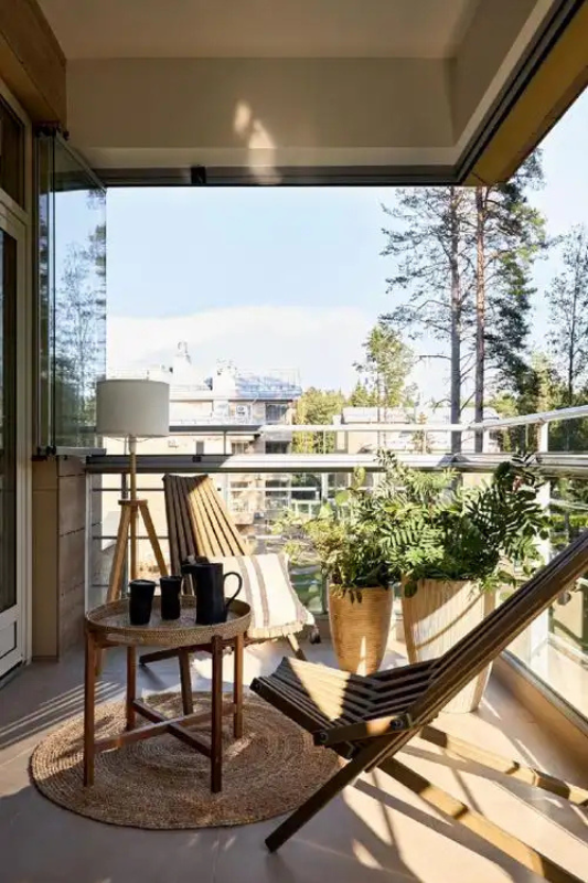Modern balcony with lounge chairs, indoor outdoor rug, and tall planters for a polished feel