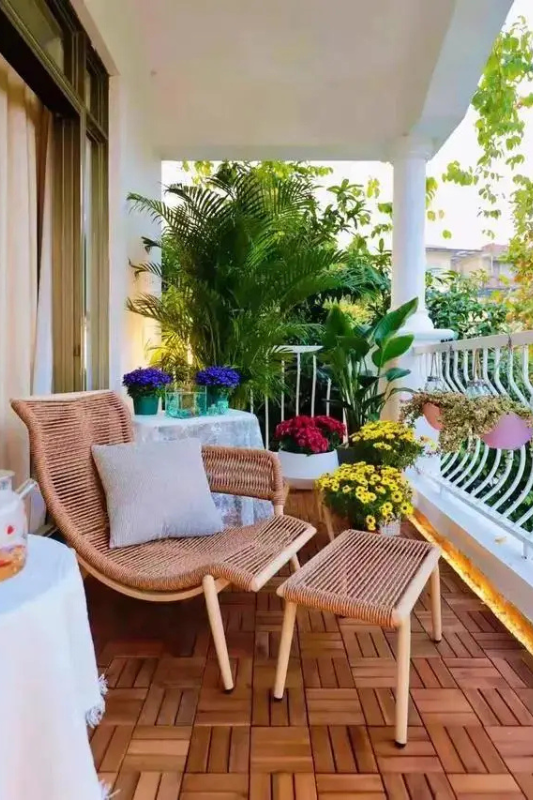 Wide apartment balcony with wicker seating, soft cushions, and layered greenery for resort style living