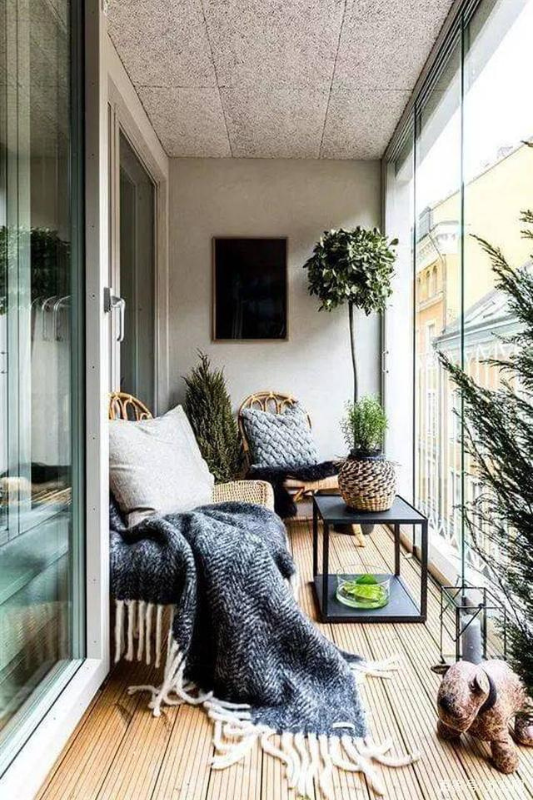 Glass enclosed balcony with rattan chairs, plants, and soft lighting creating a calm retreat
