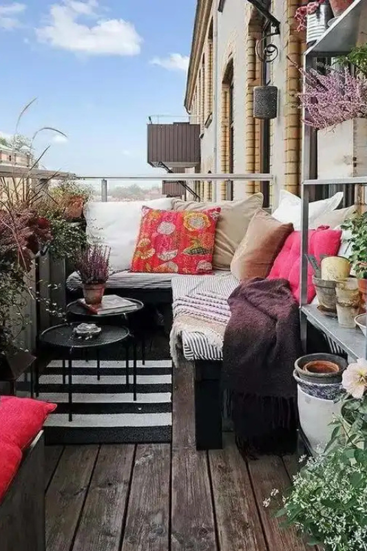 Enclosed apartment balcony with bistro seating, planters, and city views