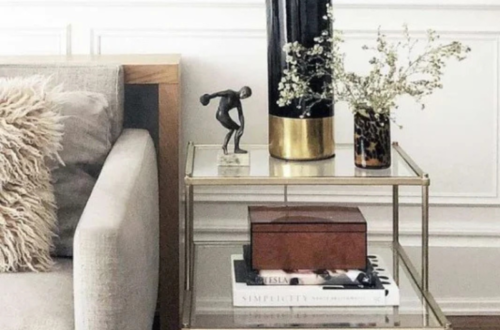End table decor styled with a lamp, books, and neutral accents beside a sofa in a living room