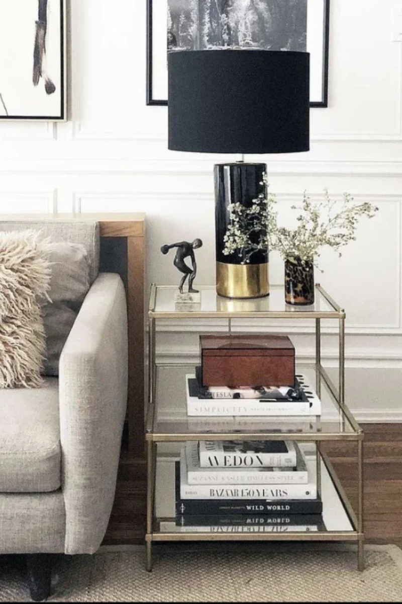 End table decor styled with a lamp, books, and neutral accents beside a sofa in a living room