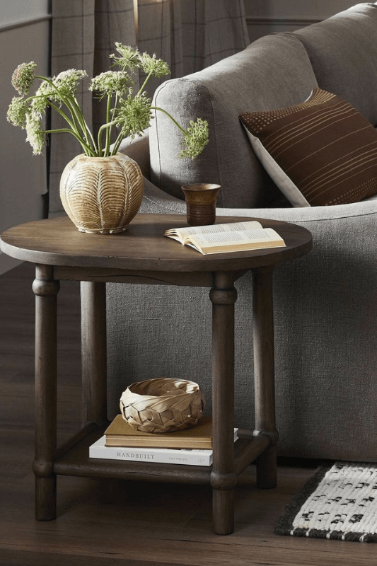 End table decor styled with a lamp, books, and neutral accents beside a sofa in a living room