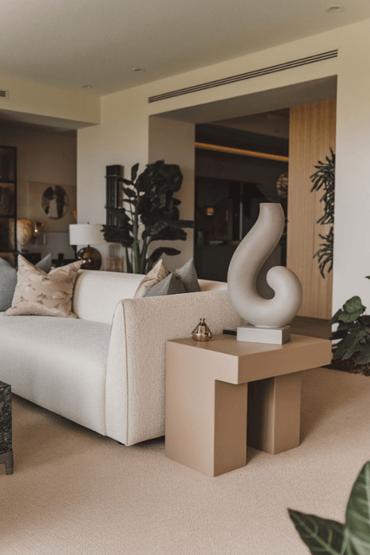 End table decor styled with a lamp, books, and neutral accents beside a sofa in a living room