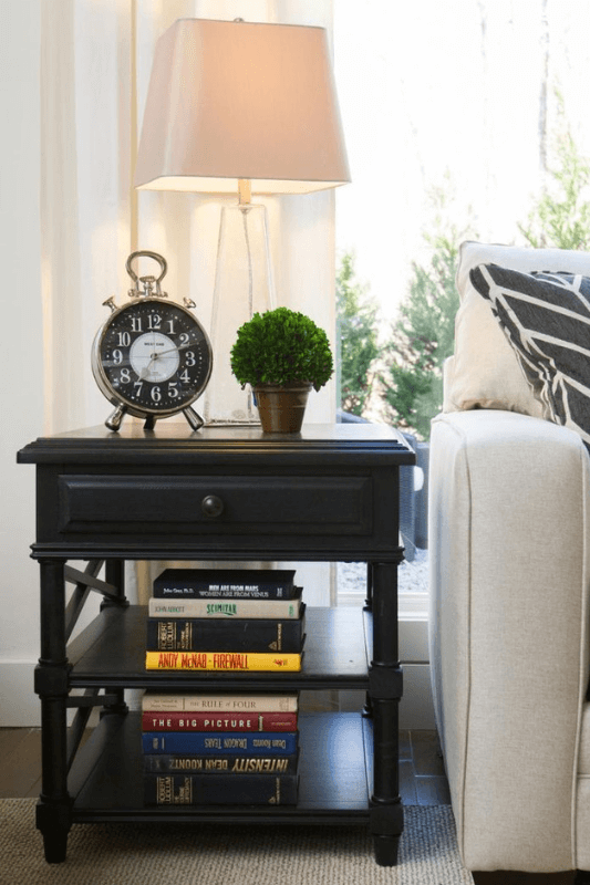 End table decor styled with a lamp, books, and neutral accents beside a sofa in a living room