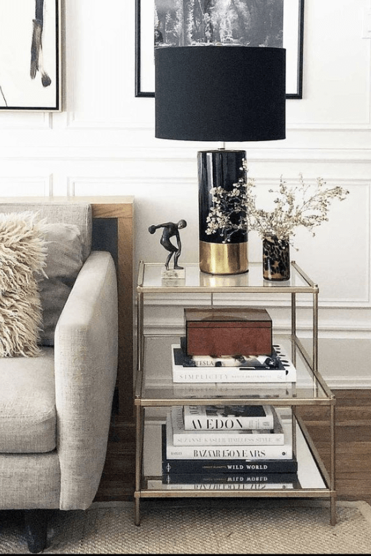 End table decor styled with a lamp, books, and neutral accents beside a sofa in a living room