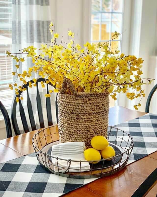 Yellow floral and lemon centerpiece in a woven basket on a summer dining table