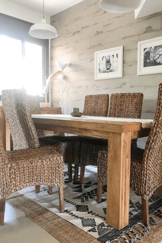 Dining room with a black and white patterned rug layered over a natural woven area rug