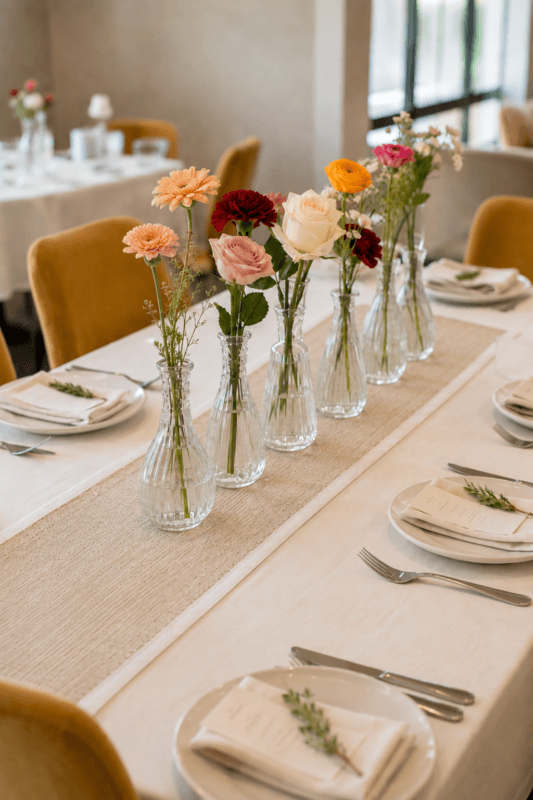 Colorful flowers in small glass bud vases for a summer dining table centerpiece