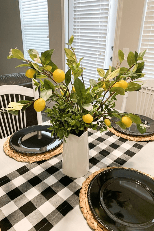 Lemon branch centerpiece in a white vase on a black and white checkered table runner