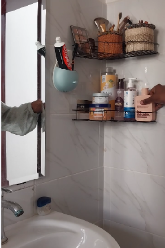 Organizing skincare products on the lower bathroom shelf with makeup stored on the top shelf
