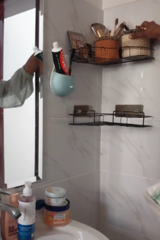 Removing skincare products while reorganizing wall shelves in a small bathroom
