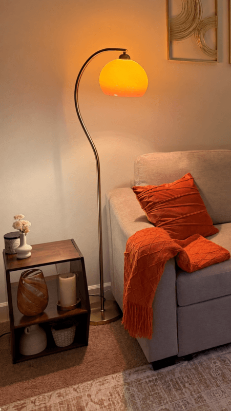 Curved floor lamp beside a sofa creating warm light around the seating area
