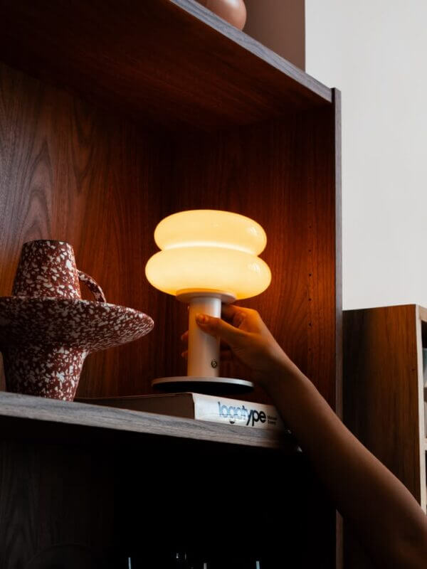 Small rechargeable accent lamp adding warm light to a dark wood bookshelf